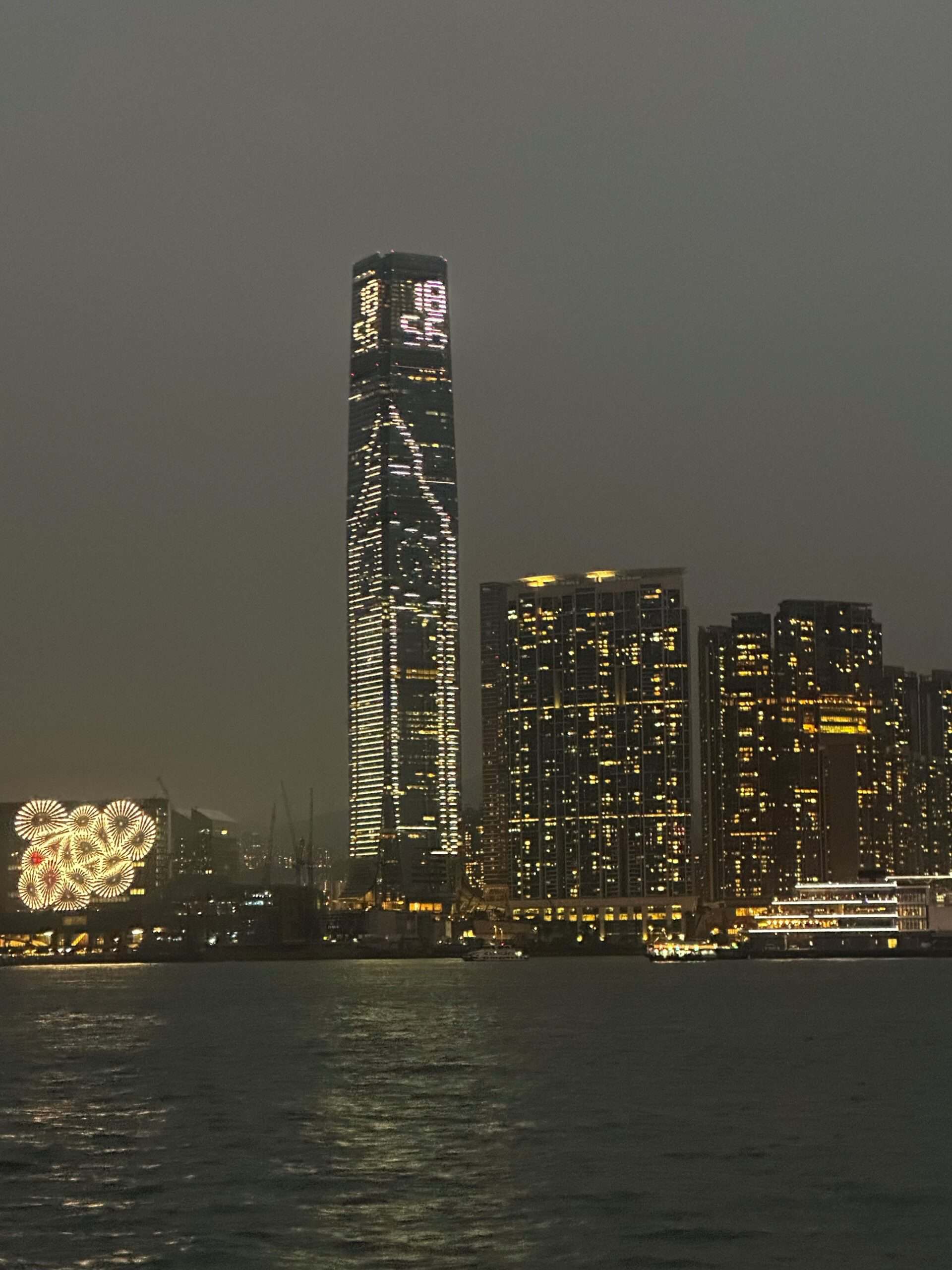 Stedelijke skyline van Hong Kong in de nacht, met verlichte wolkenkrabbers en de International Commerce Centre (ICC), reflecterend in de rivier, voor Elips Solutions – specialist in technologisch advies en digitale transformatie.