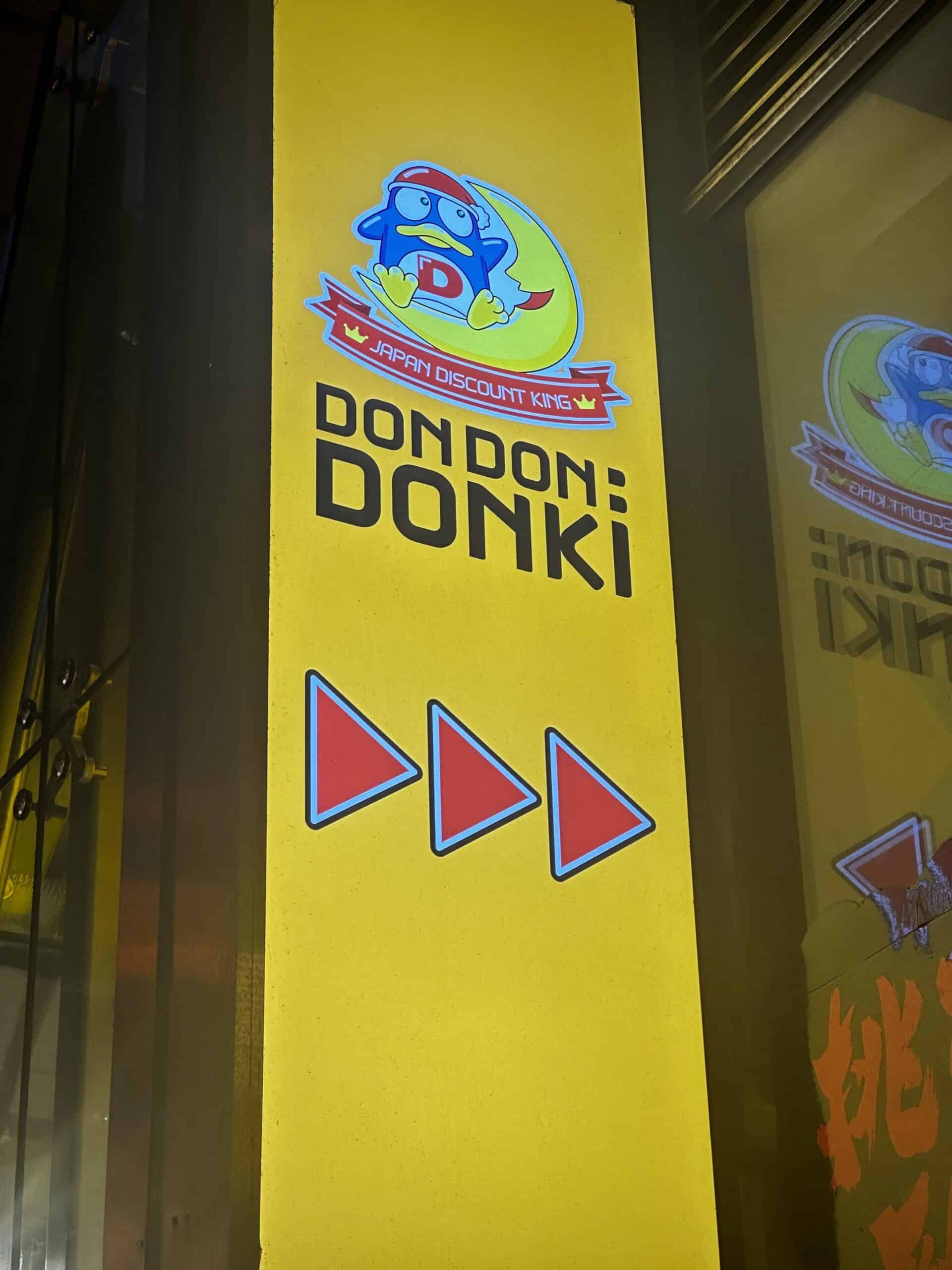 Japan Discount King logo met leeuwenkop en maan, kleurrijk ontwerp op gele achtergrond, promoting Don Don Donki winkel.