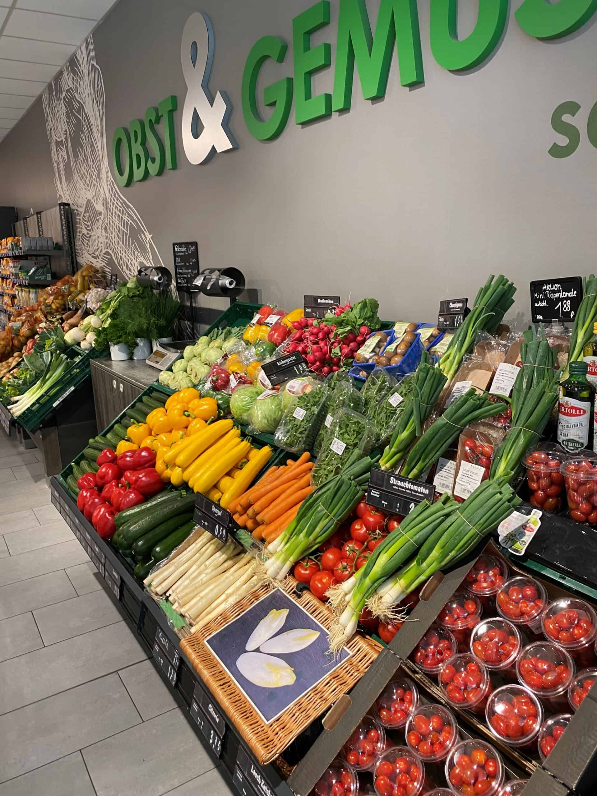 Frisse groenten en fruit in supermarkt, groenten- en fruitafdeling met kleurrijke aardbeien, tomaten, paprika's en groene uien voor gezonde voeding.