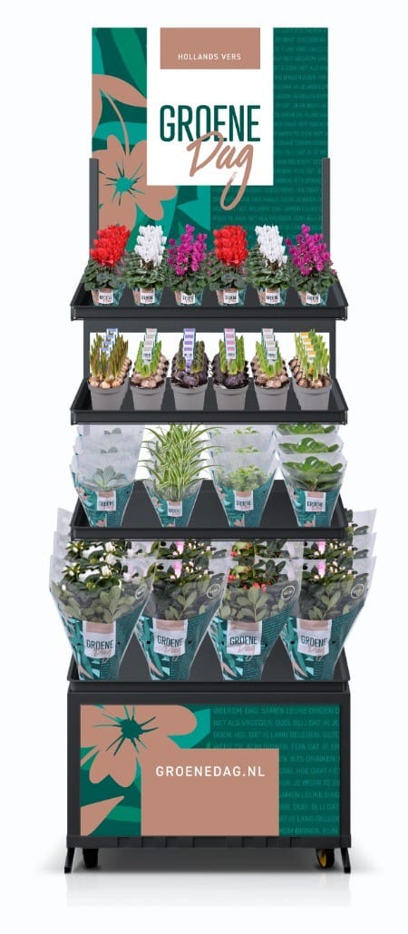 Kleurrijke bloemen- en plantendisplay met Groene Dag branding en diverse bloemen en kruiden voor tuinieren en decoratie.