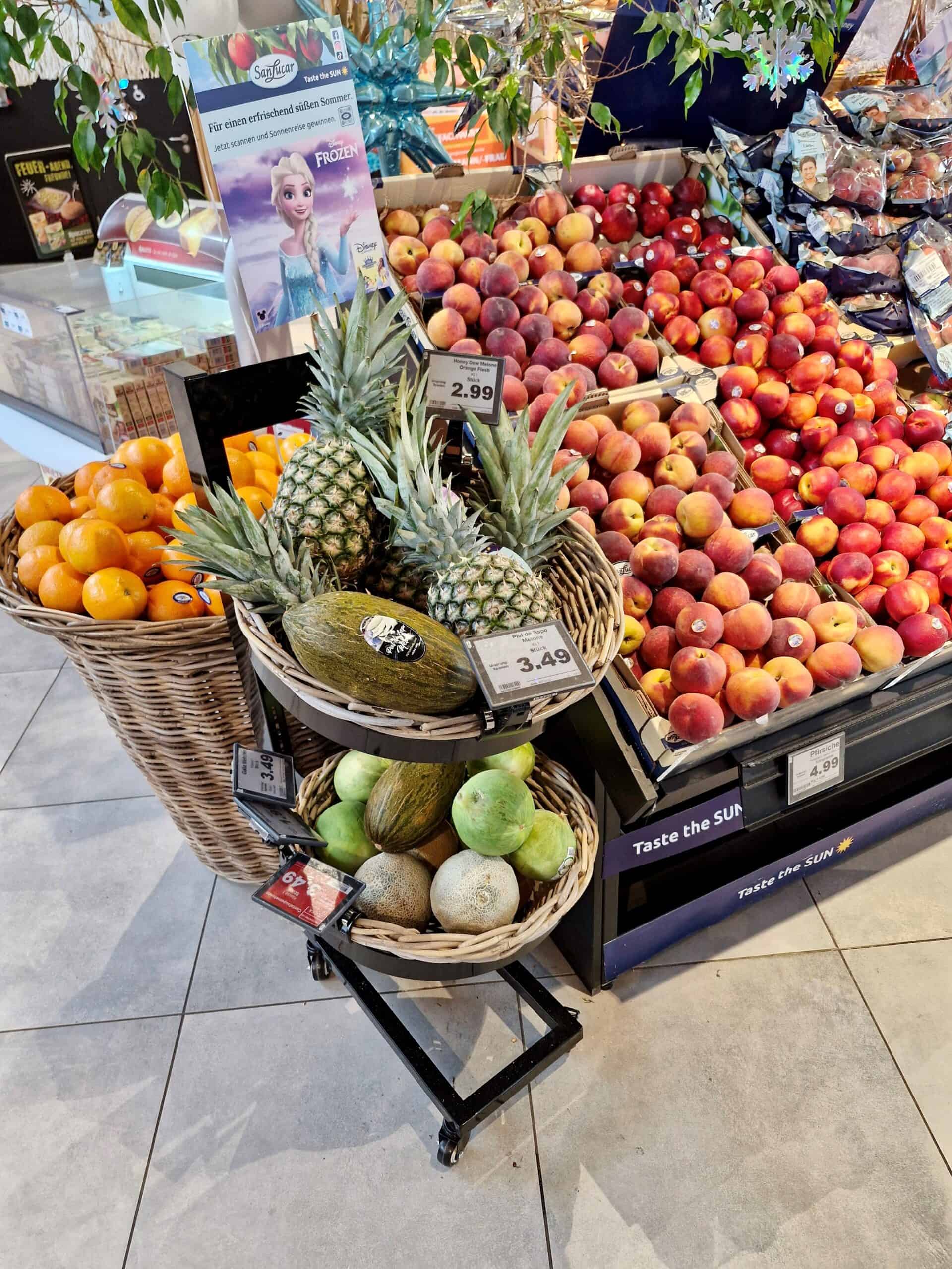 Frisse supermarktfruitdisplay met ananas, meloenen, nectarines en perziken, ideal voor gezonde voeding en vers fruit.