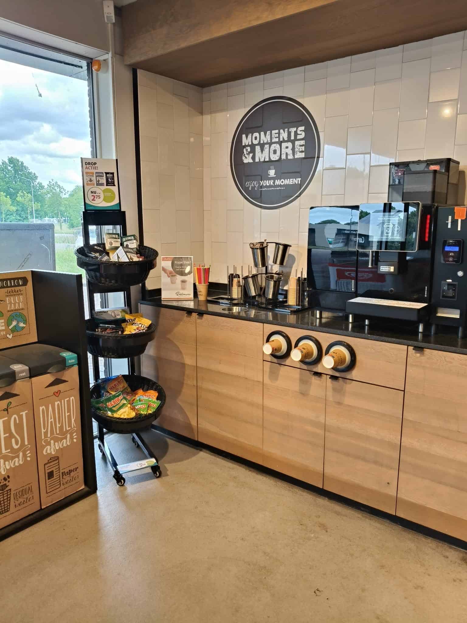 Straatbeeld van een koffiecorner met moderne koffiemachine, zachte houtaccenten en cart over wegwerpartikelen, geschikt voor horeca of kantooromgeving.