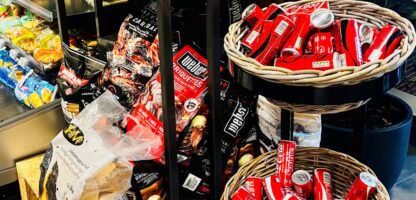 Sfeervolle supermarktdisplay met frisdranken, snacks en levensmiddelen in een moderne winkel. Perfect voor het promoten van culinaire en snackproducten bij Elips Solutions.