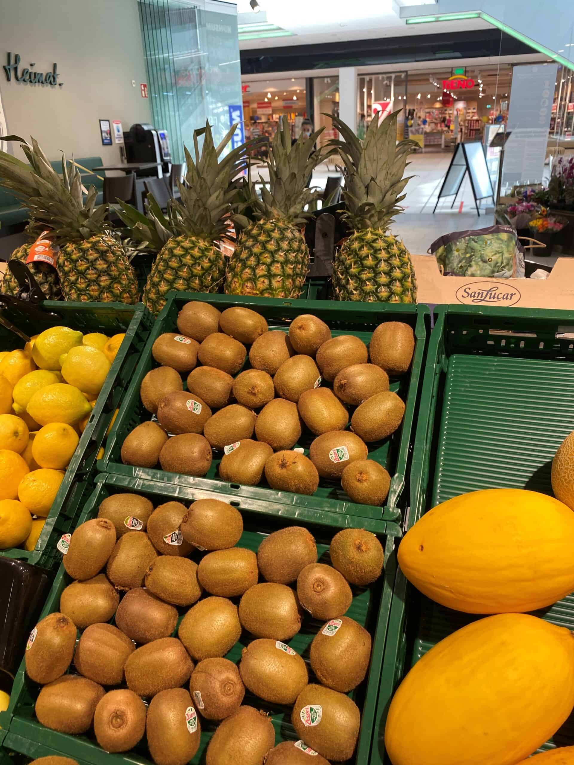 Pineapples, kiwi's en meloenen in een supermarkt, vers fruit voor gezonde eetgewoonten.