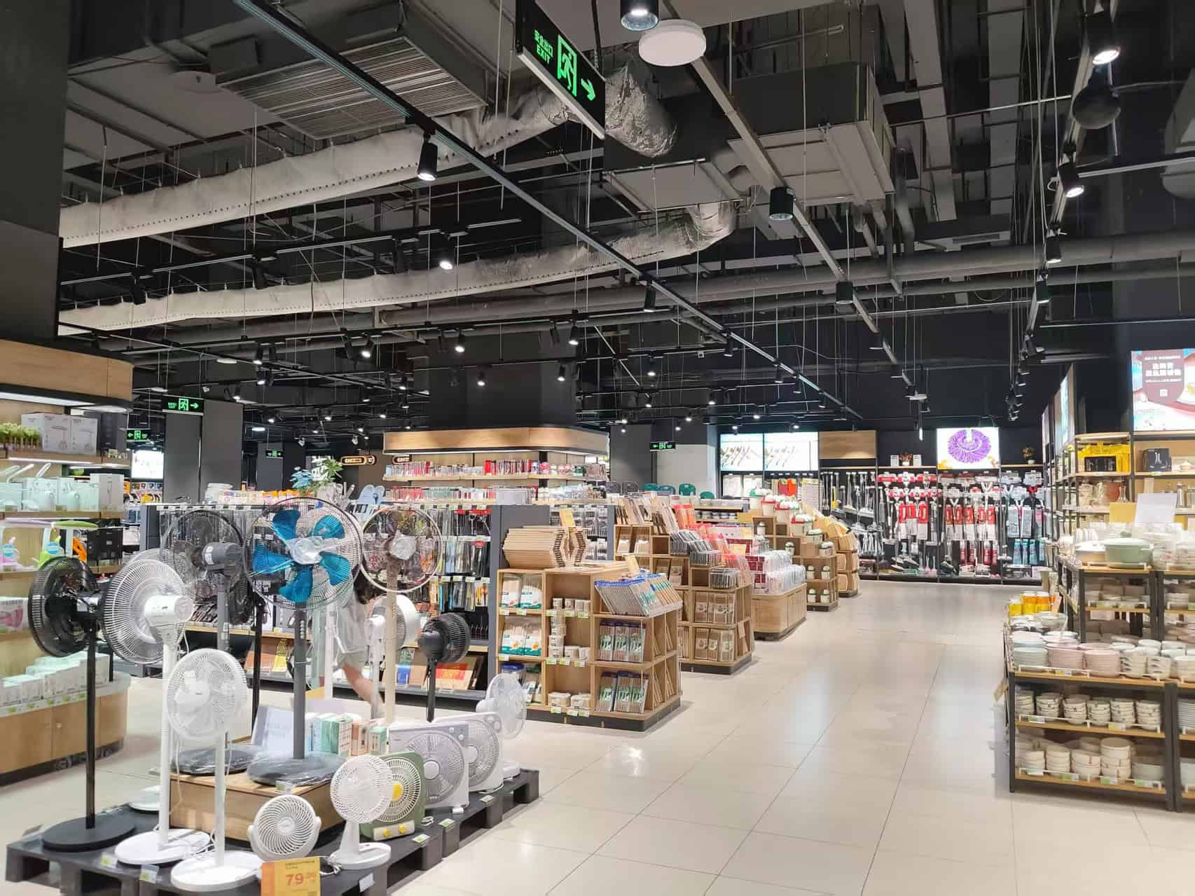 Koopinterieur van een moderne woonwinkel met diverse huishoudartikelen, keukengerei en elektrische ventilatoren in een ruime, goed verlichte retailomgeving.
