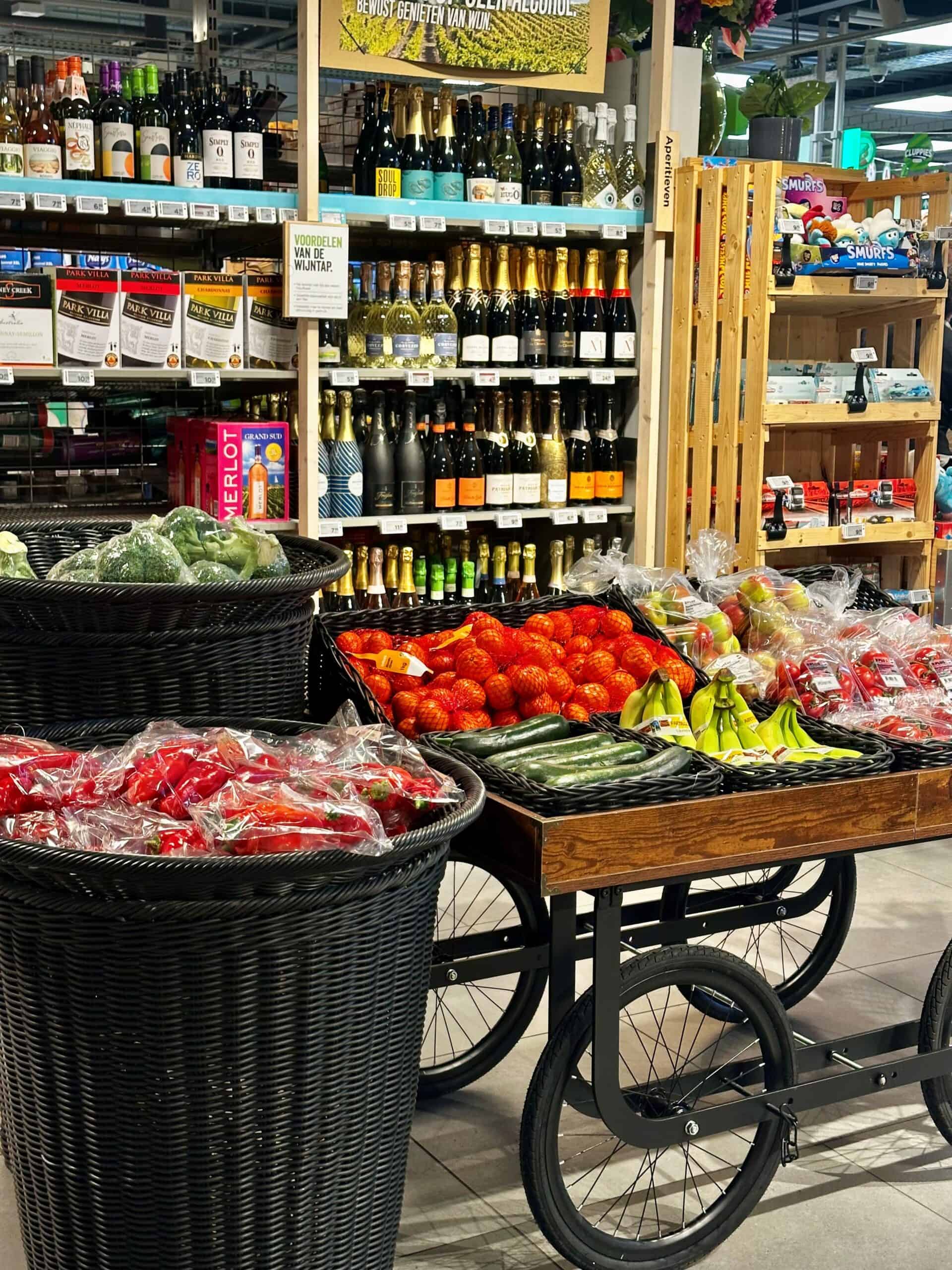 Supermarkt met vers fruit, wijn en alcoholproducten, display met groenten en flessen wijn en champagne op achtergrond, ideaal voor levensmiddelen en delicatessen, focus op versheid en assortiment.