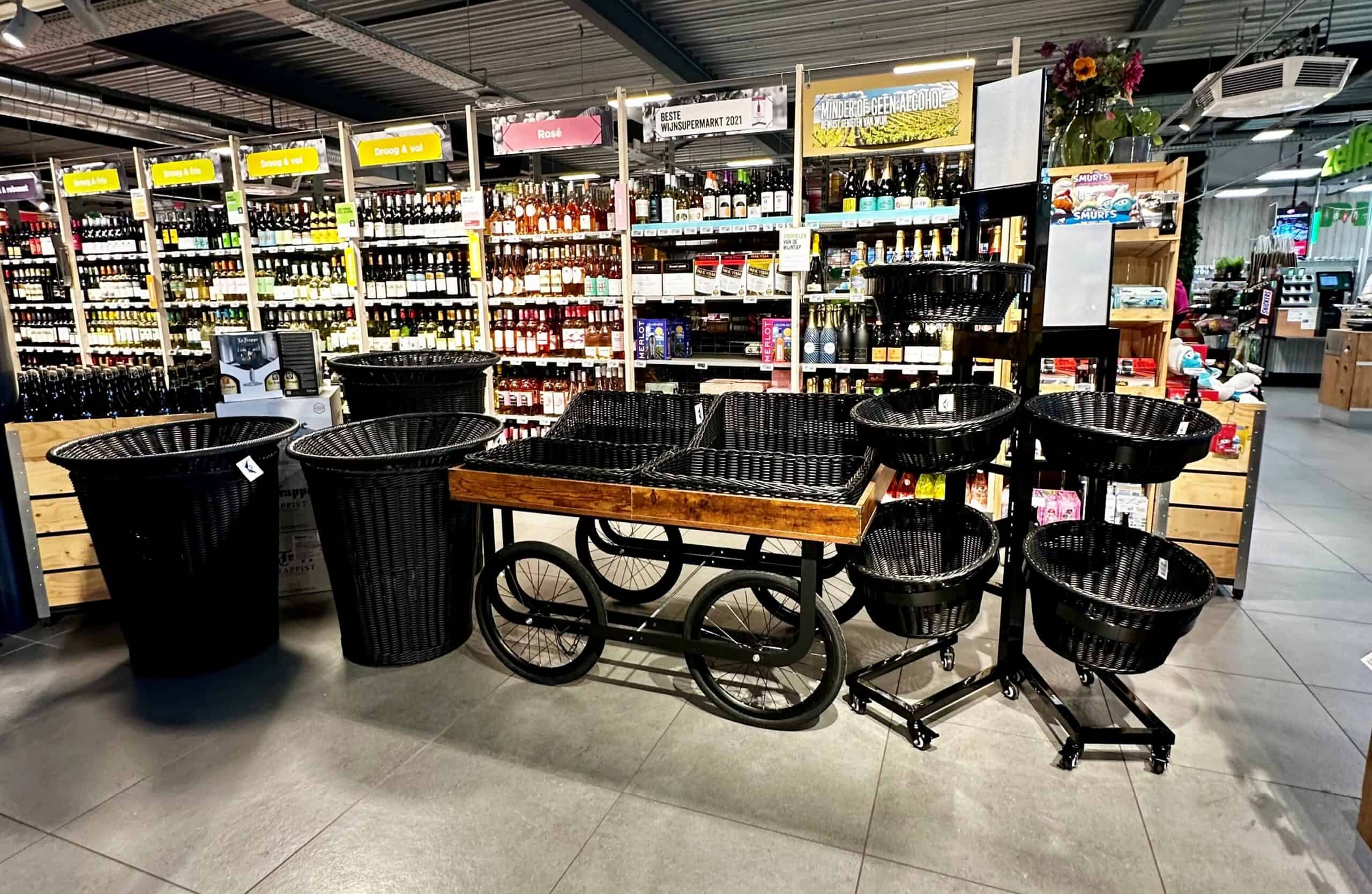 Kunststof winkelwagentjes en decoratieve manden op een display in een supermarkt, klaar voor klanten. Ruime keuze in winkelwagen- en mandvormen met een opvallende presentatie in een versmarktomgeving.