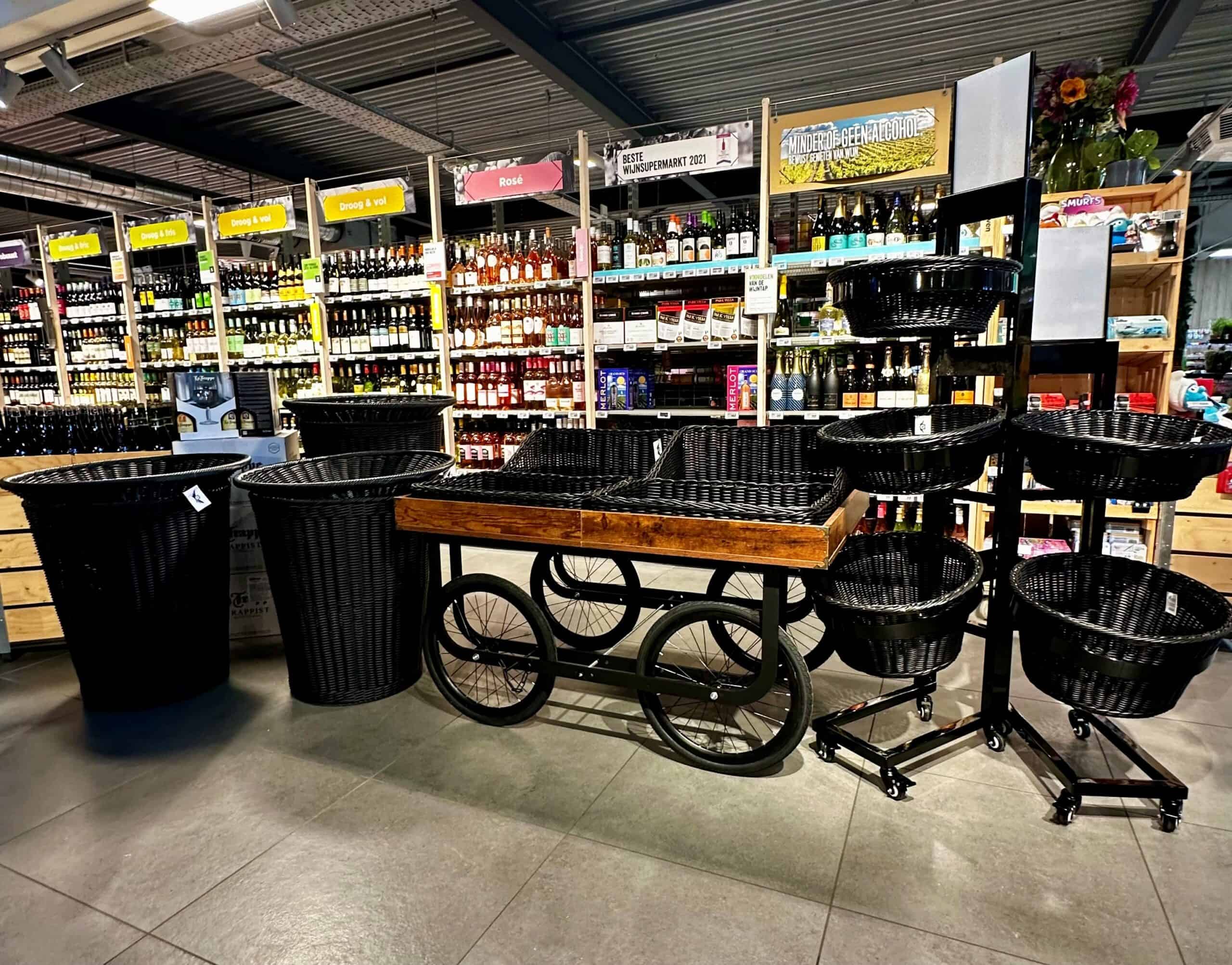 Moderne winkelinrichting met zwart wicker winkelwagens en manden, perfect voor retail en supermarkt, gecombineerd met wijnrekken en etalages in een sfeervol en georganiseerd detail.