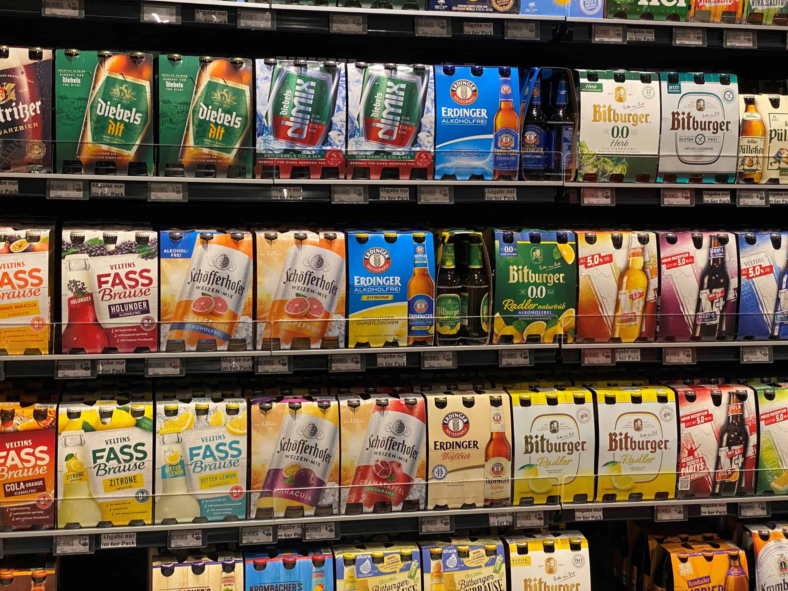 Verpakkingen van alcoholvrije en alcoholhoudende dranken op supermarktrekken, inclusief frisdranken en mixers, gericht op gezondheid en gemak.