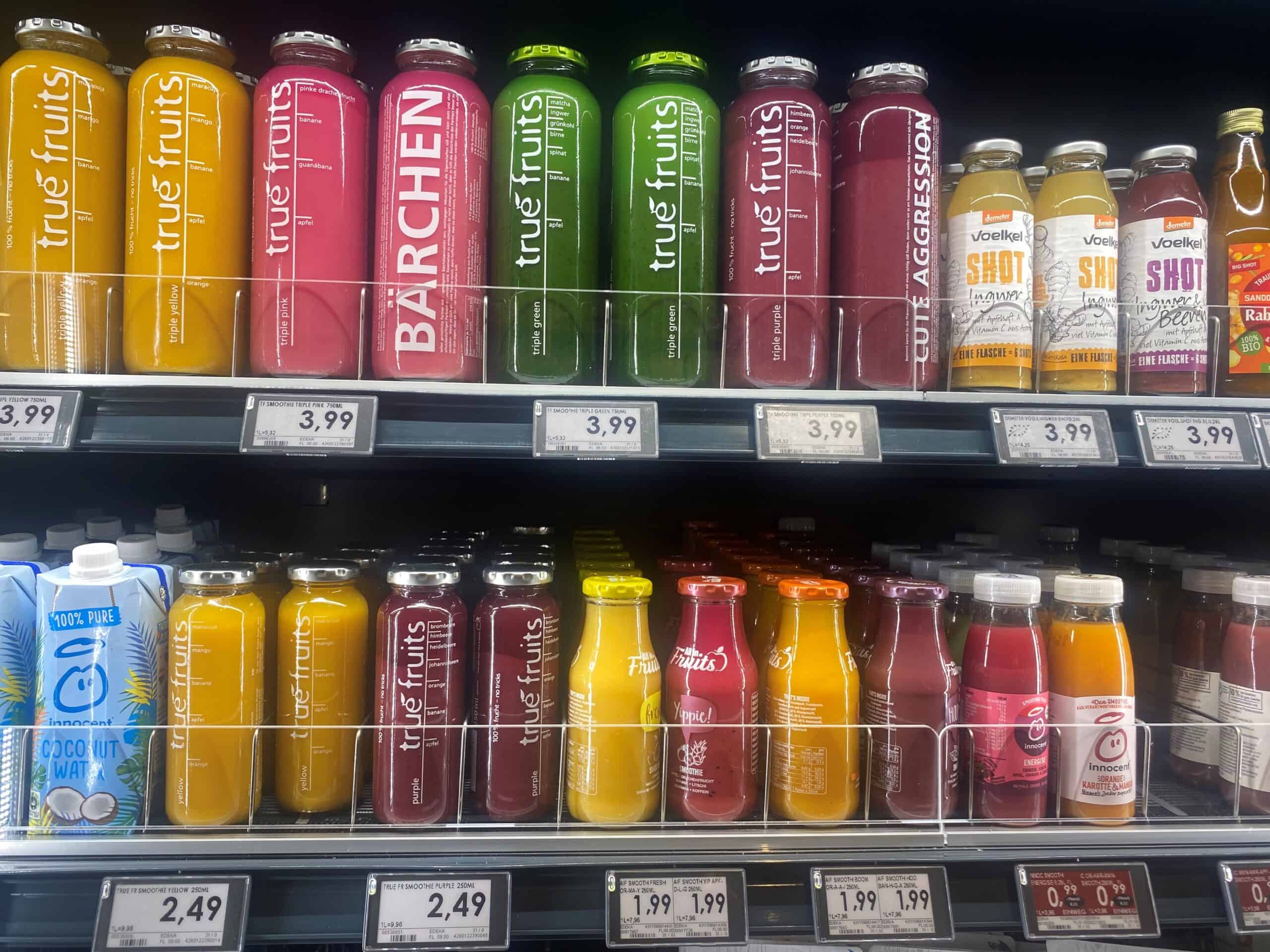 Fris vitamine- en fruitsappen op supermarktrek, kleurrijk assortiment van True Fruits, inclusief banaan, mango en bessen smaken, perfect voor gezonde levensstijl, beschikbaar voor aankoop.