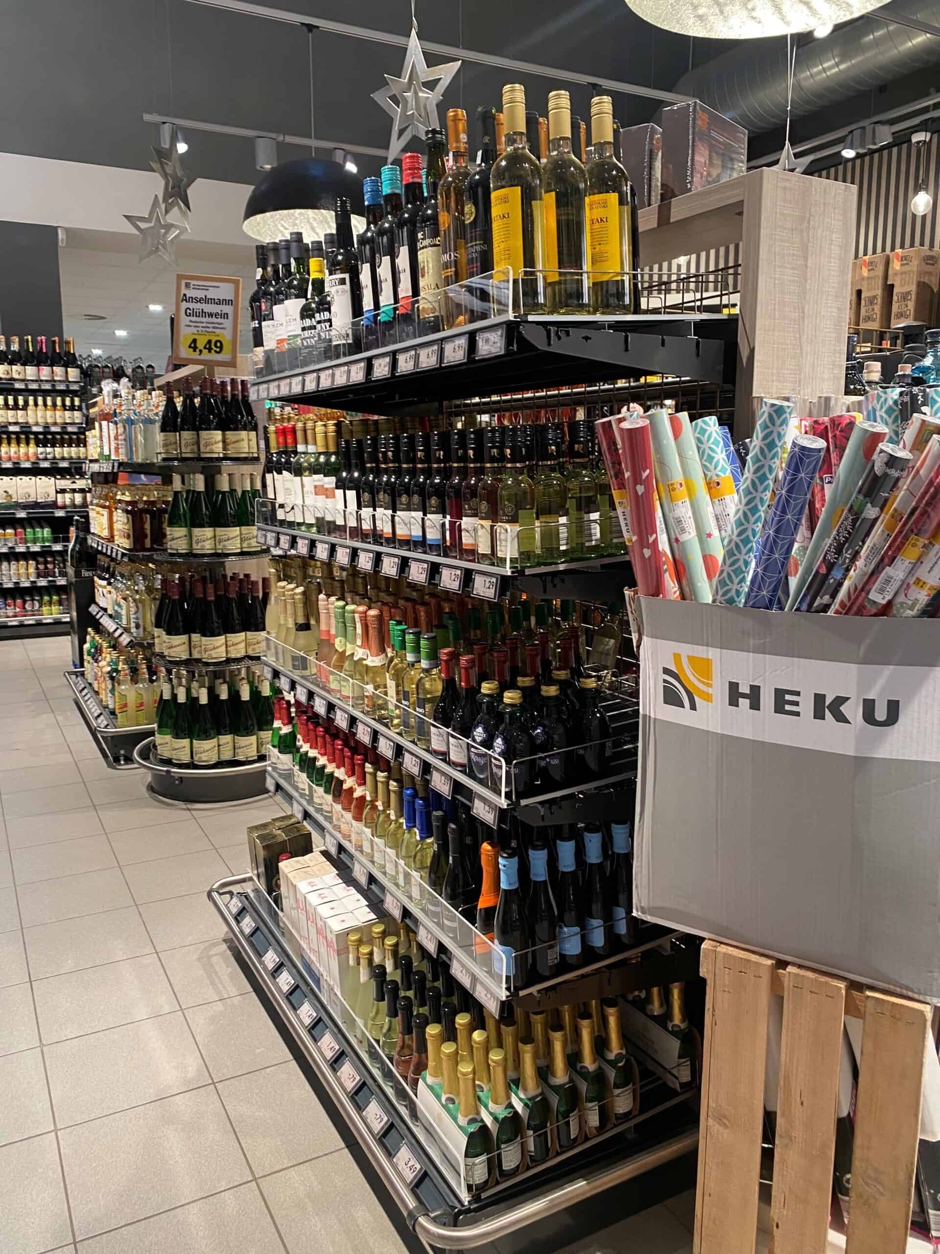 Voldoende assortiment wijn en alcoholische dranken in supermarkt, op gepaste plek uitgestald op rekken, met prijswaarschuwingsbord.