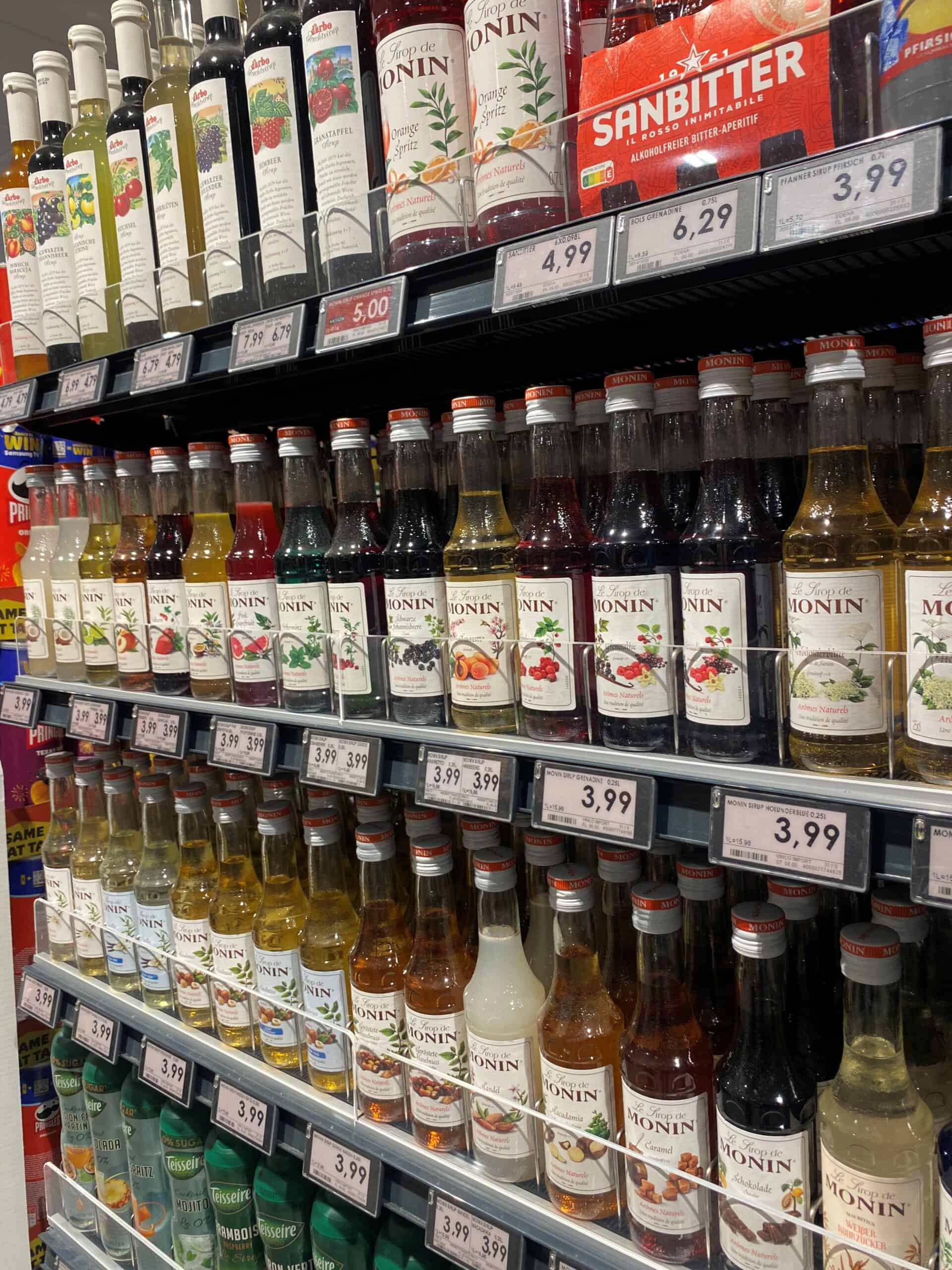 Achterkant van een supermarkt met een uitgebreide selectie van Monin siropen voor cocktails en desserts.