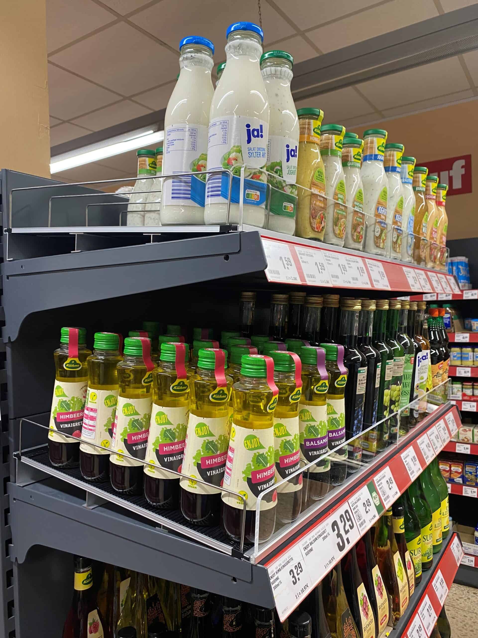 Zuivel en azijnproducten op supermarktrek, inclusief salades, vinaigrettes en azijnsappen. Verschillende merken en varianten voor gezonde voeding en koken.