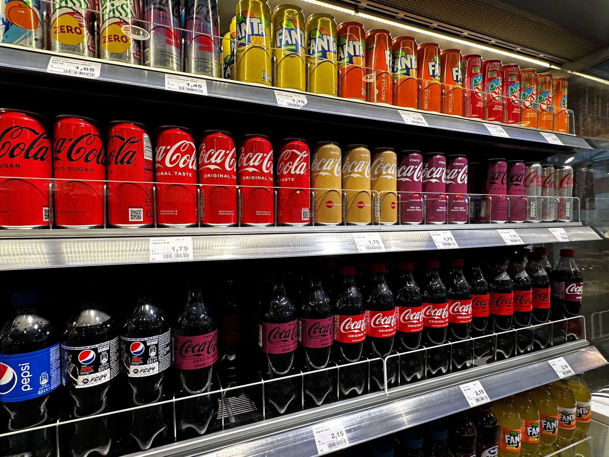 Blik op frisdrank display met Coca-Cola, Fanta en Pepsi voorraad in supermarkt. Verkoop van diverse frisdrankmerken en smaken, ideaal voor retail en horeca.