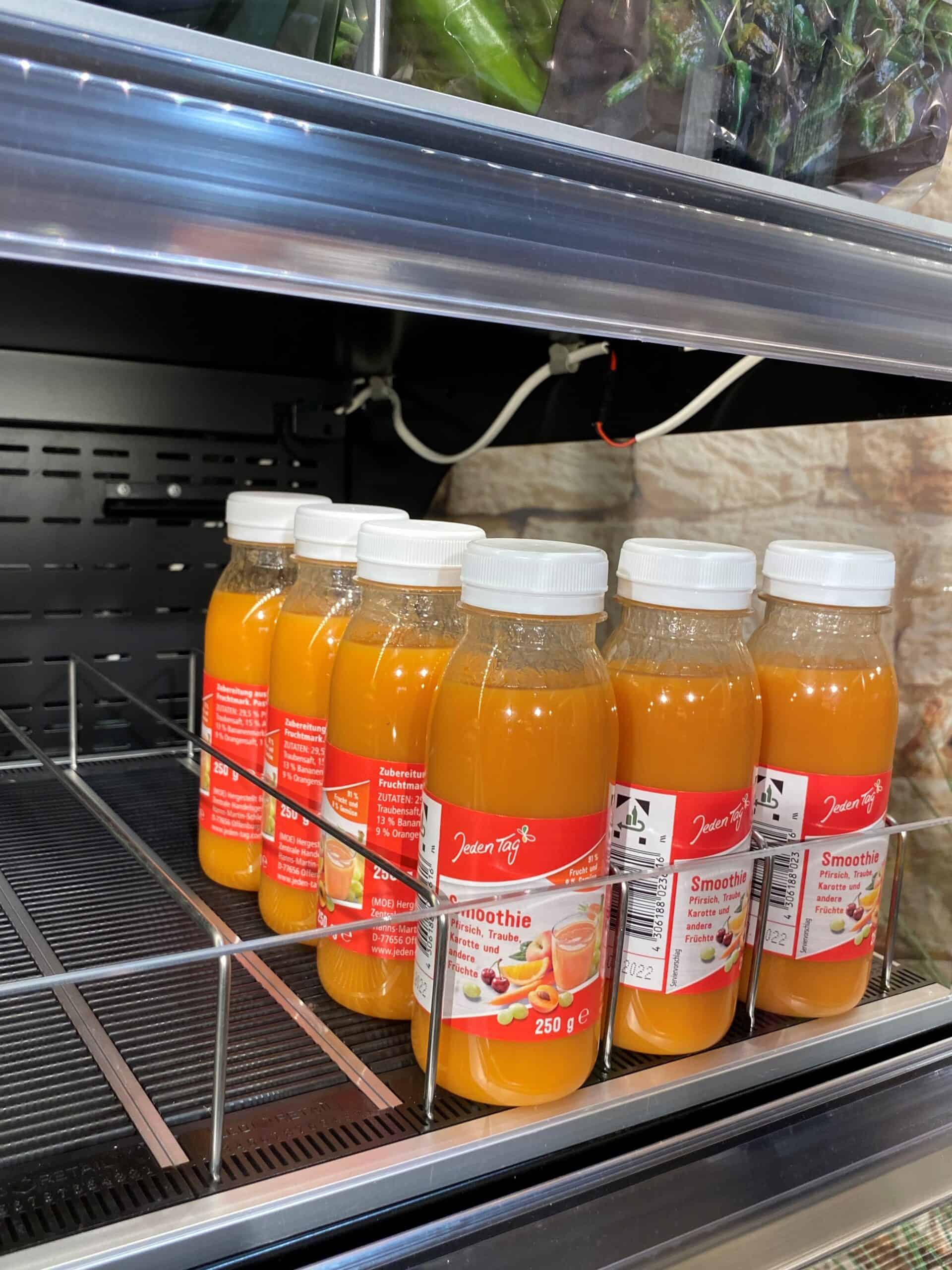 Zeer verse fruit- en groentesmoothies in glazen flessen op een gekoelde display. Perfect voor gezonde levensstijl en versgeperste juice aanbiedingen bij Elips Solutions.