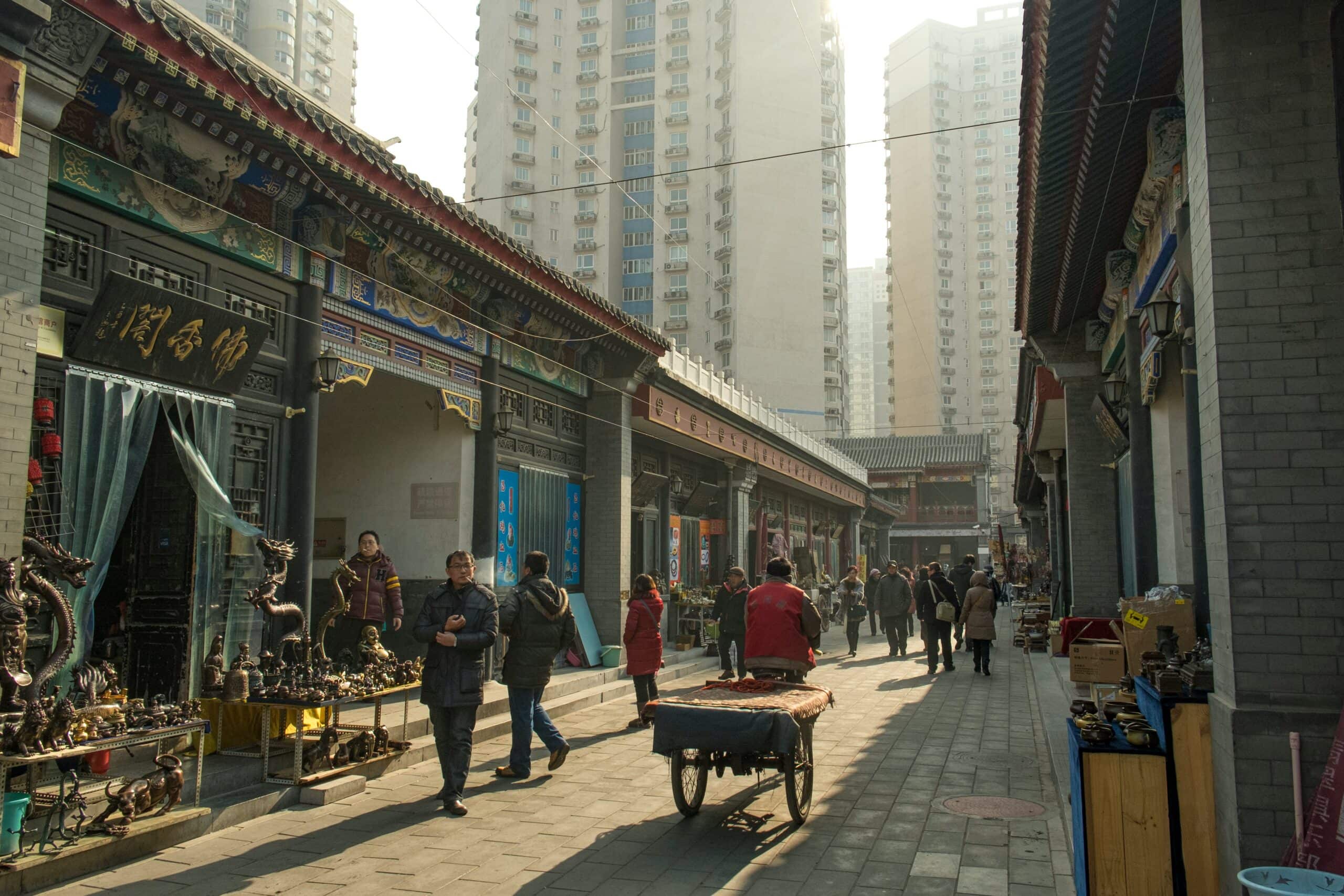 Kunst- en handwerksmarkt in een traditioneel Chinese buurt met hoge moderne gebouwen op de achtergrond.