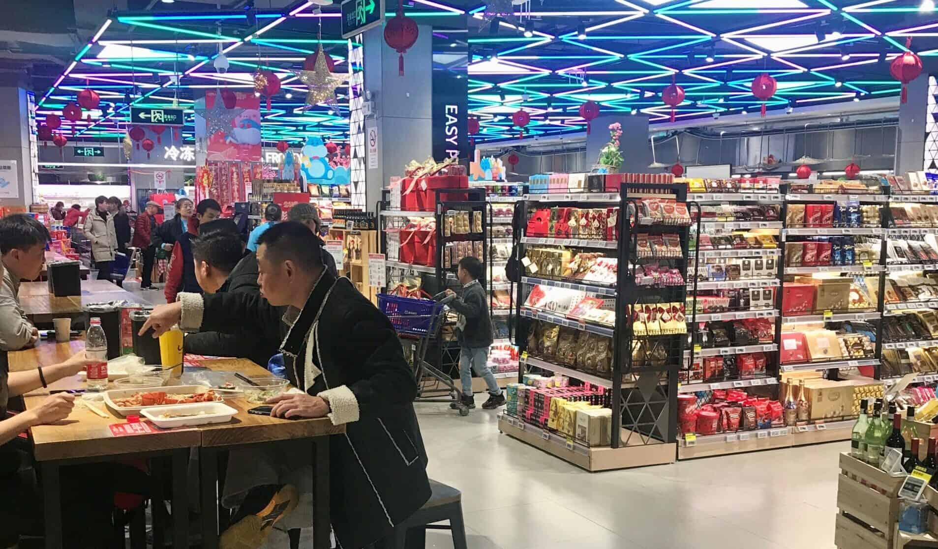 Winkel in een hypermarkt met feestdagen versieringen en mensen die winkelen en eten drinken.