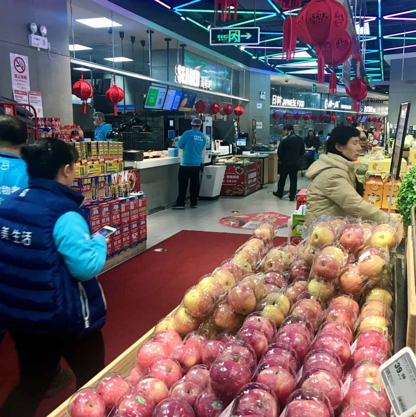Producten van een supermarkt, fruitafdeling met appels, kleurrijk en vers,in een winkelomgeving met klanten en personeel, binnen, Chinese supermarkt, feestdecoraties en verlichting, merchandising, kwaliteitsproducten, moderne winkelindeling.