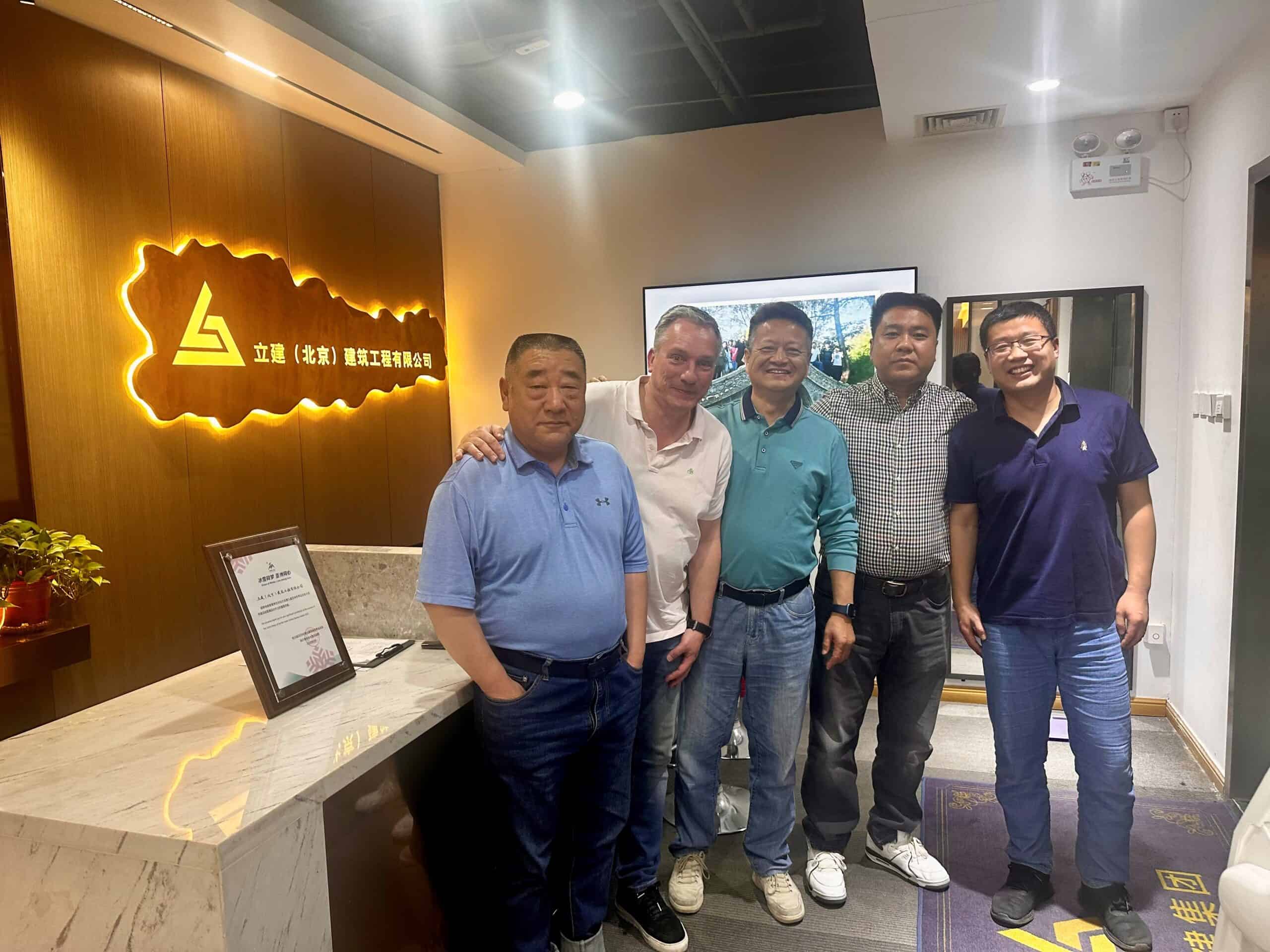 Kleine groep lachende mensen tijdens zakelijke bijeenkomst bij Elips Solutions in China, met logo en ontvangstbalie op de achtergrond.